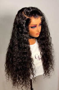 Person wearing a long, curly black wig on a plain background